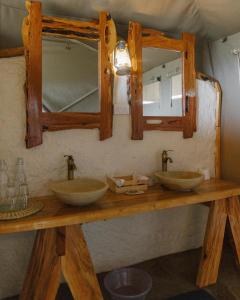 due lavandini su un bancone in legno con uno specchio di Enchipai Mara Camp a Musiara Campsite