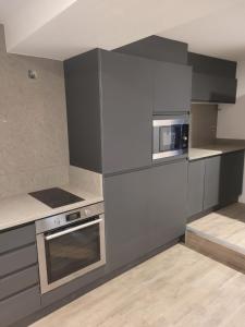 a kitchen with gray cabinets and a microwave and a stove at 10 Hockenhall - Liverpool's Oldest House in Liverpool