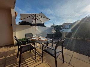 a table with chairs and an umbrella on a patio at Le Hameau du Phare - La Chaume 100 m plage in La Chaume +12 photos