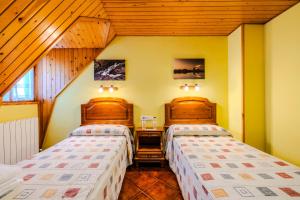 two beds in a room with wooden ceilings at Hostal Pañart in Bielsa