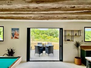 a dining room with a ping pong table and a pool at Bâtisse au cœur du Gers in Leboulin