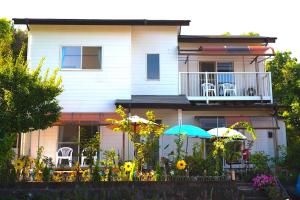 a house with chairs and umbrellas in front of it at Grace House グレイスハウス- Country Home Relaxation in Okawa