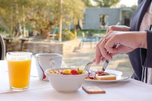 a person eating a plate of food and a bowl of fruit at Brit Hotel Nantes Vigneux - L'Atlantel in Vigneux-de-Bretagne