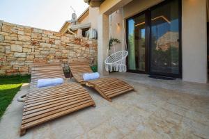 two wooden benches on a patio next to a stone wall at Casa Lucca in Bale