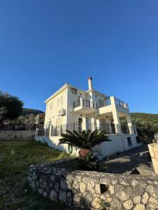 a large white house with a palm tree in front of it at Stunning View Villa in Sami in Chaliotata