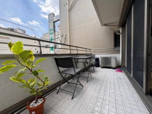 a balcony with chairs and a table and a plant at Comfy House Namba in Osaka