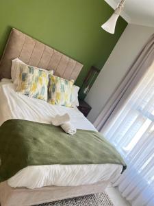 Una cama con un animal de peluche sentado encima. en Olive Luxe at The Blyde, en Pretoria