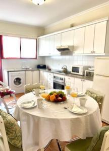 einen weißen Tisch mit einer Schale Obst und Weingläsern in der Unterkunft Casa da Palmeira Porto Santo in Vila Baleira