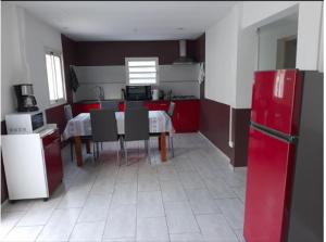 a kitchen with a table and chairs and red cabinets at Pomme de Pin in Cilaos