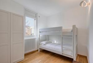 a white bedroom with a bunk bed and a window at San Siro Apartment in Milan