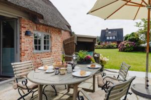 a table and chairs on a patio with an umbrella at Kapitänshaus Joana in Westerland (Sylt)