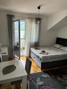 a bedroom with a bed and a table and a balcony at Zora Apartment in Plužine