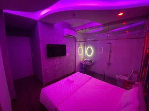 a purple room with a bed and a tv at Sakura Hotel Thủ Đức in Ho Chi Minh City