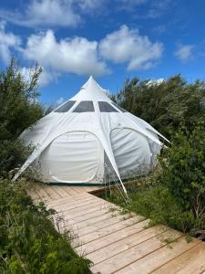 una grande tenda bianca seduta su una passerella di legno di Agger Glamping - Fyret a Vestervig