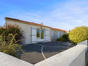 a building with white doors and a driveway at Maison pour 4 entre plages et marais salants in Les Bussolleries