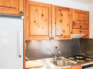 a kitchen with wooden cabinets and a sink at Apartment Grand Place 5 by Interhome in Nendaz
