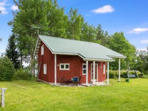 a red cabin with a green roof in a field at Holiday Home Villa talvilahti by Interhome in Sotkamo