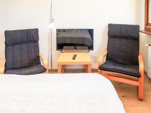 twee stoelen in een kamer met een bed en een televisie bij Apartment Rosablanche D35 by Interhome in Siviez