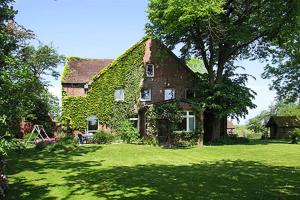a large brick house with ivy growing on it at Ferienwohnung auf dem Hof Tjarks in Friedrichsschleuse