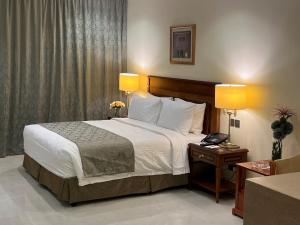 1 dormitorio con 1 cama con 2 lámparas y teléfono en Al Gosaibi Hotel - Villa, en Al Khobar 124 fotos más