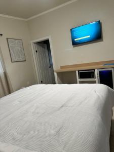 a bedroom with a white bed with a flat screen tv on the wall at Hotel Mision Ferrer in San Vicente