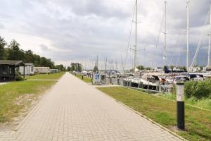 a brick path next to a marina with boats at Ferienwohnung Hafenhus in Peenemünde