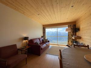 un salon avec un canapé et une grande fenêtre dans l'établissement Homency Résidence Signal B16, à L'Alpe-d'Huez
