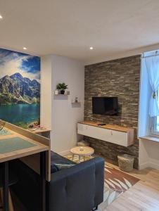 a living room with a tv on a brick wall at Appartement au cœur des Alpes in Albertville