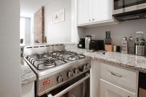 a kitchen with a gas stove and white cabinets at Fashionable 1-Bedrm Apt 15 Min to Manhattan in Hoboken +8 photos