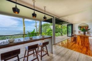 a kitchen and dining room with a bar and large windows at Bali Villa Jungle Paradise - Uvita in Uvita