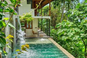 a pool in the middle of a house with a waterfall at Bali Villa Jungle Paradise - Uvita in Uvita