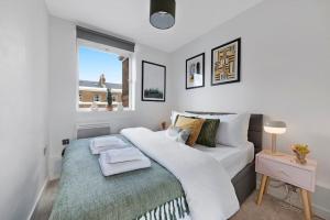 a bedroom with a large white bed and a window at Modern and Airy Belgravia Living in London