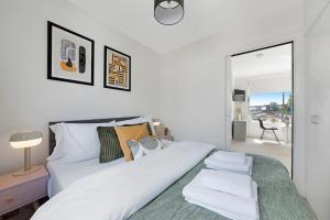 a white bedroom with a white bed and a balcony at Modern and Airy Belgravia Living in London