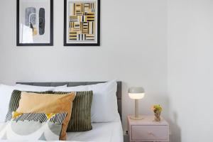 a bedroom with a bed with pillows and a table with a lamp at Modern and Airy Belgravia Living in London