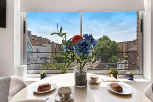 a vase of flowers on a table in front of a window at Modern and Airy Belgravia Living in London