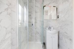 a white bathroom with a shower and a sink at Modern and Airy Belgravia Living in London