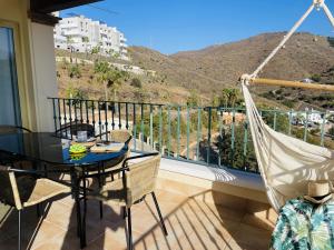 - un balcon avec un hamac, une table et des chaises dans l'établissement Apartamento Altos de Tamango con vistas y pisicina, à Torrox Costa