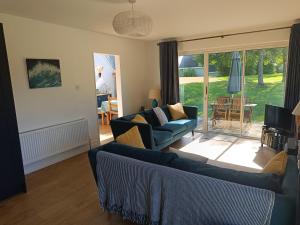 a living room with two couches and a sliding glass door at Cottage on the grounds of Rathmullan House Hotel in Rathmullan