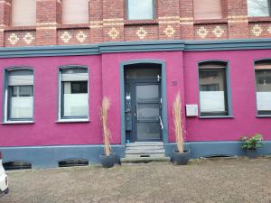 a pink house with two potted plants in front of it at Ostwind in Bochum