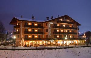 a large building with lights in the snow at night at Albergo Conca Verde in Fiera di Primiero
