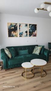 a living room with a green couch and two tables at Odiseea Apartment-Private parking included in Sibiu