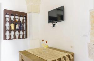 a table with a wine glass and a tv on a wall at Emerald Suites - Villa Emerald in San Vito dei Normanni