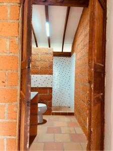 a bathroom with a toilet and a brick wall at Villa carmelita in Jardin