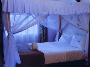 a bedroom with a canopy bed with a window at SUMMERDAY PALACE in Mtwapa +13 photos
