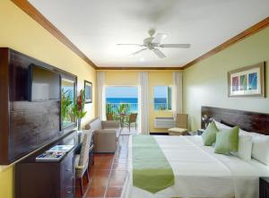 a hotel room with a bed and a television at Coconut Court Beach Hotel in Bridgetown