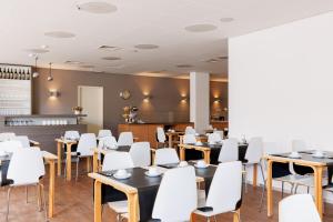 a dining room with tables and white chairs at Hotel Cavalli by WP Hotels in Blankenberge