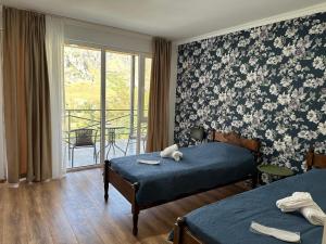 una camera d'albergo con due letti e un balcone di Hotel-GVALA a Vardzia