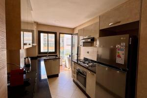 a kitchen with a stainless steel refrigerator and a stove at Luxury Appart Tamaris - Piscine Jardin et Plage à Pied in Tamaris