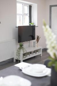 a living room with a tv and a table with plants at Budget 2-Bed House 10mins to Leeds City Centre in Leeds