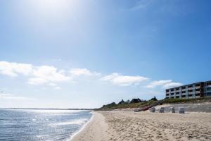 Una playa con una hilera de sillas de playa y un edificio. en Strandliebe, en Dikjendeel